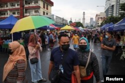 Para pengunjung mengenakan masker saat berbelanja makanan untuk berbuka puasa di pasar Ramadhan, di tengah pandemi COVID-19, di Kuala Lumpur, Malaysia, 15 April 2021. (REUTERS / Lim Huey Teng)