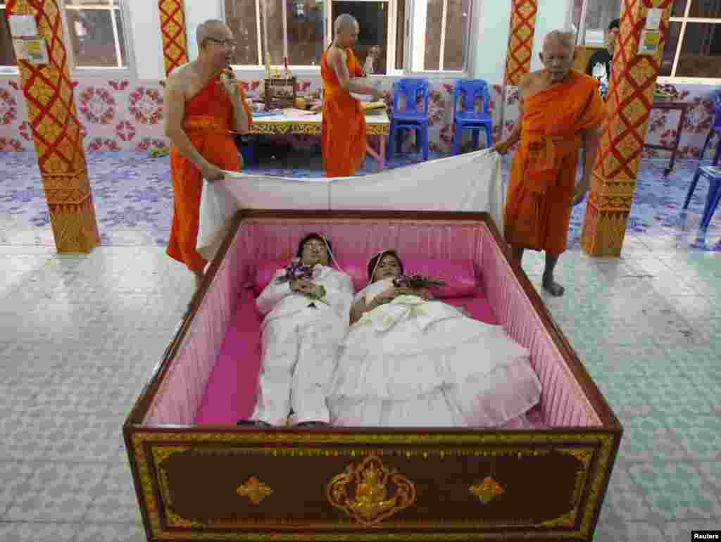 Groom Tanapatpurin Samangnitit and his bride Sunantaluk Kongkoon, lie in a coffin during a wedding ceremony at Wat Takien temple in Nonthaburi province, on the outskirts of Bangkok, Thailand. Seven couples laid in the pink coffin during the wedding ceremony organized by the Buddhist temple on Valentine&#39;s Day. Couples believe laying briefly in the coffin will get rid of bad luck and usher happiness into their lives.