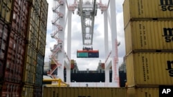 FILE - A crane removes a container from a ship at the Port of Baltimore's Seagirt Marine Terminal in Baltimore.The government reports the U.S. trade deficit has fallen to its lowest level since since October 2009.