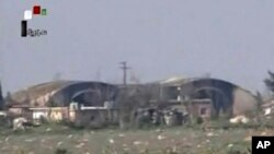 FILE - This frame grab from video provided April, 7, 2017, by official Syrian TV shows the burned and damaged hangars hit by U.S. Tomahawk missiles at the Shayrat air base southeast of Homs, Syria.