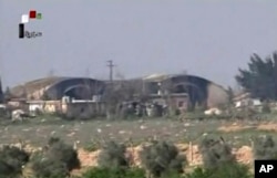 FILE - This frame grab from video provided April, 7, 2017, by official Syrian TV shows the burned and damaged hangars hit by U.S. Tomahawk missiles at the Shayrat air base southeast of Homs, Syria. Syrian warplanes resumed flights from the air base Sunday, a Syrian regional official claimed.