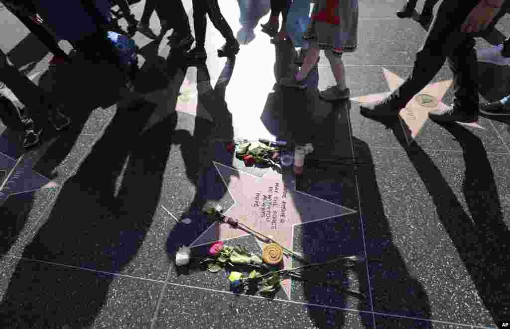 People walk past an impromptu memorial created on a blank Hollywood Walk of Fame star by fans of late actress and author Carrie Fisher, who does not have an official star on the world-famous promenade, in Los Angeles, California, Dec. 28, 2016.