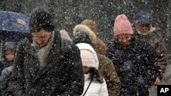 FILE- Pedestrians walk through wet snow in the Brooklyn borough of New York, March 10, 2017.