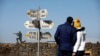 FILE - A couple look towards signs pointing out distances to different cities, on Mount Bental, an observation post in the Israeli-occupied Golan Heights that overlooks the Syrian side of the Quneitra crossing, Israel, Jan. 21, 2019. 