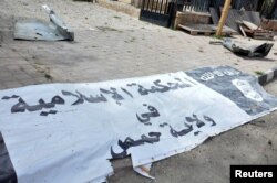 FILE - A banner belonging to the Islamic court of the Islamic State is seen on the ground after forces loyal to Syria's President Bashar al-Assad recaptured Palmyra city in this handout picture provided by SANA on March 27, 2016.