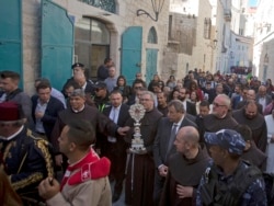 Christian clergymen carry a wooden relic believed to be from Jesus' manger outside the Church of the Nativity, traditionally believed by Christians to be the birthplace of Jesus Christ, in the West Bank city of Bethlehem, Saturday, Nov. 30, 2019.