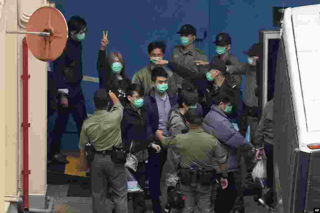 Former lawmaker Leung Kwok-hung, known as &quot;Long Hair,&quot; second left, shows a victory sign as some of the 47 pro-democracy activists are escorted by Correctional Services officers to a prison van in Hong Kong.