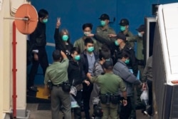 FILE - Former lawmaker Leung Kwok-hung, known as "Long Hair," second left, shows a victory sign as some of the 47 pro-democracy activists are escorted by Correctional Services officers to a prison van in Hong Kong, Thursday, March 4, 2021.