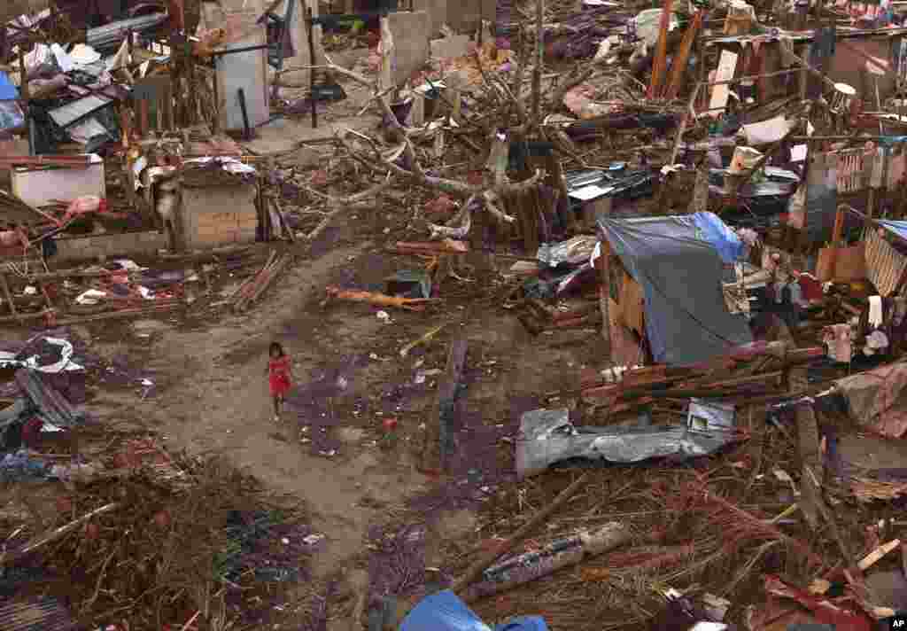 A young girl walks amid ruins of houses in a neighborhood badly affected by Typhoon Haiyan in Guiuan, Philippines, Nov. 15, 2013. 