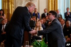 President Donald Trump shakes hands with acting Department of Veterans Affairs Secretary Robert Wilkie after announcing he will nominate him to lead the department during an event on prison reform in the East Room of the White House, May 18, 2018.