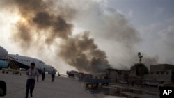 Smoke rises above the Jinnah International Airport where security forces continue to battle militants Monday, June 9, 2014, in Karachi, Pakistan. Gunmen disguised as police guards attacked a terminal with machine guns and a rocket launcher during a five-h