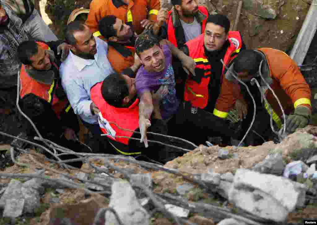 2012年11月18日，巴勒斯坦民防隊員幫助一名從廢墟救出來的倖存者。他的房屋在以色列空襲加沙市時被摧毀。