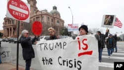 Carolyn Hursh, right, and Joey Daniel, carry a sign during a protest with others in downtown Fort Worth, Texas, Feb. 18, 2019. People gathered on the Presidents Day holiday to protest President Donald Trump's recent national emergency declaration.