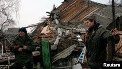 Geopolitical instability, as in eastern Ukraine, could undermine global economic growth, a new U.N. report warns. Here, a pro-Russian rebel and a resident view remnants of a house shelled near Donetsk, Ukraine, Dec. 14, 2014. 