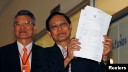 Thailand's Attorney Director General, Department of Special Litigation Chutichai Sakhakorn (R) holds filed charge papers as Director General, Department of Investigation, Surasak Threerattrakul looks on at the Supreme Court in Bangkok, February 19, 2015.