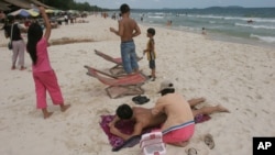 A Cambodian woman gives massage to a tourist on the beach of Sihanoukville, some 185 kilometers (115 miles) southwest of Phnom Penh, file photo. 