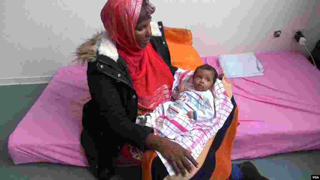 Abukar Ali Rahma, migrante, porte dans ses bras sa petite fille, Sophhia, attendant la réponse à sa demande d&rsquo;asile, dans un centre de réfugiés près de Düsseldorf, Allemagne, octobre 2015. (A. Osman / VOA)