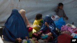 FILE - Afghan refugee families wait at the office of United Nations High Commissioner for Refugees to register to go back to Afghanistan, in Peshawar, Pakistan, April 27, 2017.