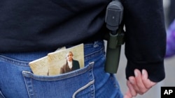 FILE - A woman wears a gun in a holster next to two copies of the U.S. Constitution during a gun rights rally at the Capitol in Olympia, Wash.