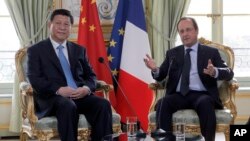 FILE- French President Francois Hollande, right, addresses Chinese President Xi Jinping during a meeting at the Elysee Palace in Paris, France, March 26, 2014.