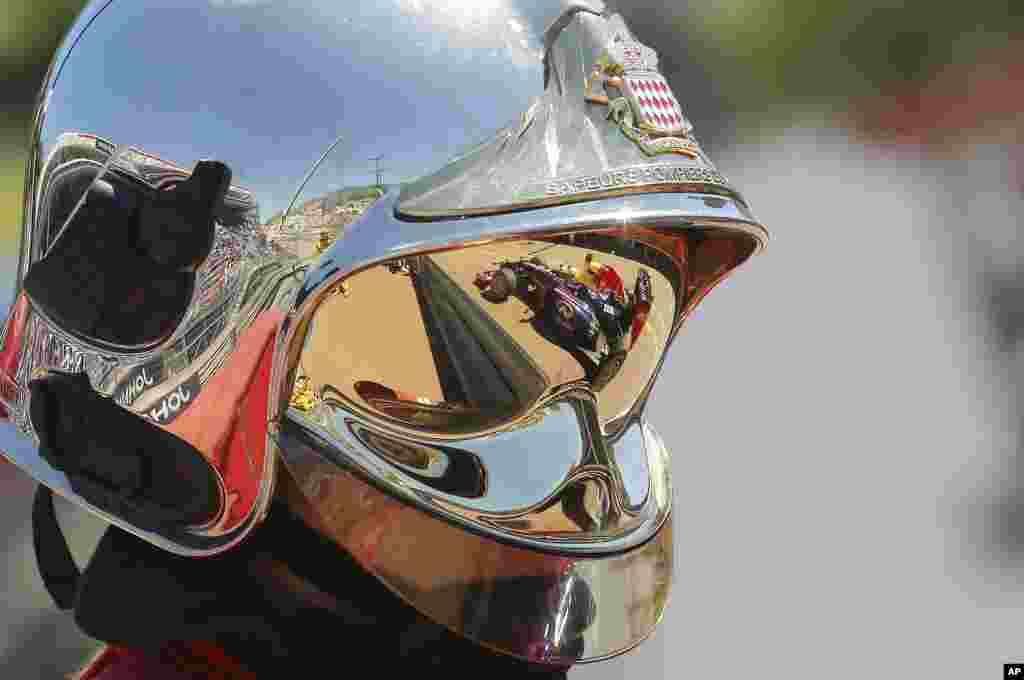 Xe v&agrave; tay đua Sebastian Vettrel người Đức phản chiếu tr&ecirc;n mũ bảo hộ của nh&acirc;n vi&ecirc;n cứu hỏa tại buổi chạy thử cho giải Monaco.