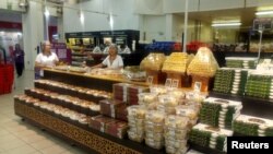 FILE - Workers stand next to food items in a shopping mall in Doha, Qatar, June 8, 2017. The IMF says some costs have gone up in Qatar as a result of a diplomatic rift that led four Arab countries to cut ties with the small Gulf state.
