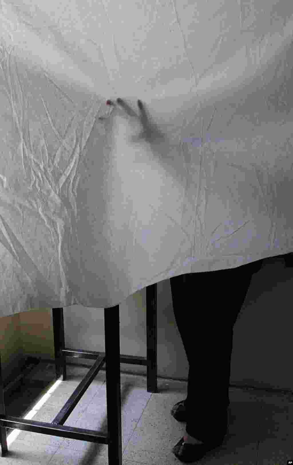 A woman votes behind a curtain during parliamentary elections in Damascus. (Reuters)