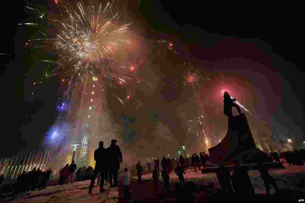 A small crowd gathers as fireworks light up the sky in Reykjavik, Iceland, Dec. 31, 2020. 