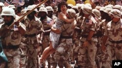 FILE - After breaking through police lines, Debi Kahn, of New Jersey, jumps into the arms of a returning Gulf War veteran during New York's Welcome Home Parade, June 11, 1991. 