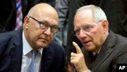 Menteri Keuangan Jerman Wolfgang Schaeuble, kanan, berbicara dengan Menteri Luar Negeri Perancis Michel Sapin dalam pertemuan meja bundar menteri-menteri keuangan zona euro di gedung EU Lex di Brussels, 12 Juli 2015. 