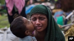 Seorang anak Rohingya Muslim mencium ibunya saat mereka beristirahat setelah melintasi perbatasan Myanmar dan Bangladesh di perbatasan dekat kawasan Teknaf Cox Bazar, 2 September 2017 (foto: AP Photo/Bernat Armangue)