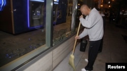 A man sweeps up broken glass after a riot swept through the area in protest to the election of Republican Donald Trump as President of the United States in Portland, Oregon, U.S., Nov. 10, 2016.