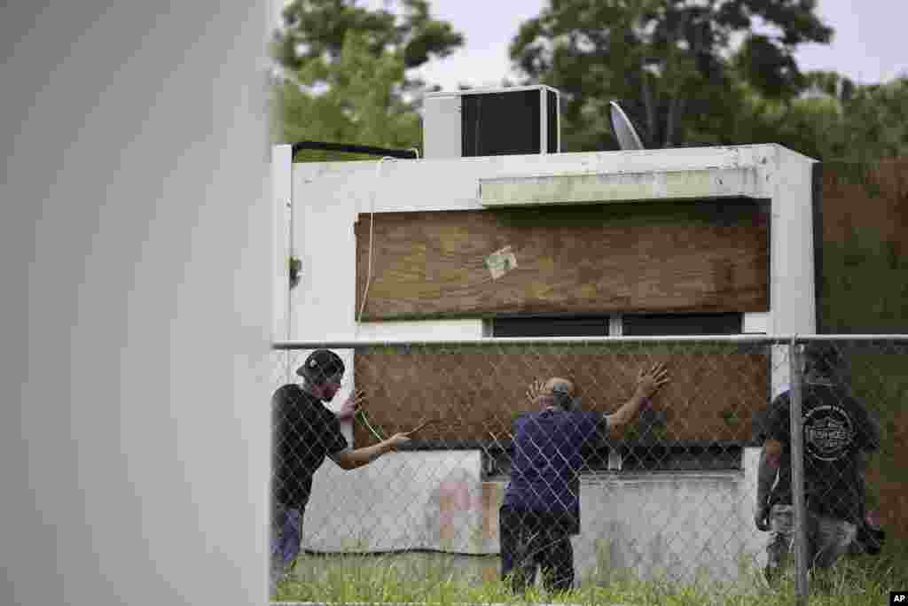 Residentes de la comunidad de Las Lomas, en Ceiba, Puerto Rico, tapan con madera las ventanas en preparación para el huracán Irma, que ya ha comenzado a abatirse en la isla. Puerto Rico ha declarado estado de emergencia por la tormenta. AP Sept. 6, 2017.