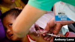  FILE - In this Feb. 16, 2019, file photo, Philippine National Red Cross and Health Department volunteers conduct house-to-house measles vaccination to children at an informal settlers community in Manila, Philippines.