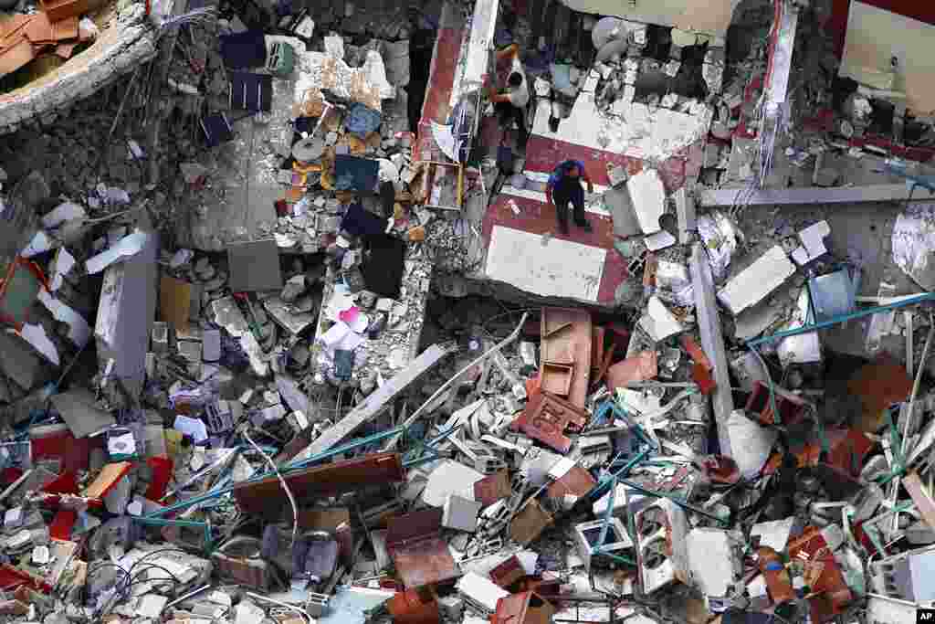 Palestinians inspect the destroyed building housing the offices of The Associated Press and other media, which was hit last week by Israeli airstrikes, in Gaza City, after a cease-fire took effect.
