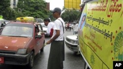 A member of the Democratic Party (Myanmar) hands out political booklets on the party to a taxi driver during their election campaign in downtown Rangoon, Burma, 19 Oct 2010