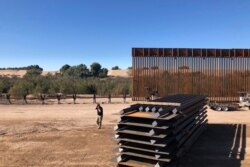 FILE - In this Jan. 10, 2020, photo, people work at a portion of border wall which is under construction in Yuma, Ariz.