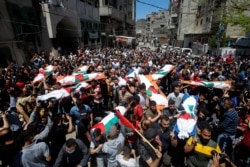 Mourners carry the bodies of Palestinians who were killed amid a flare-up of Israeli-Palestinian violence, during their funeral at the Beach refugee camp, in Gaza City, May 15, 2021.