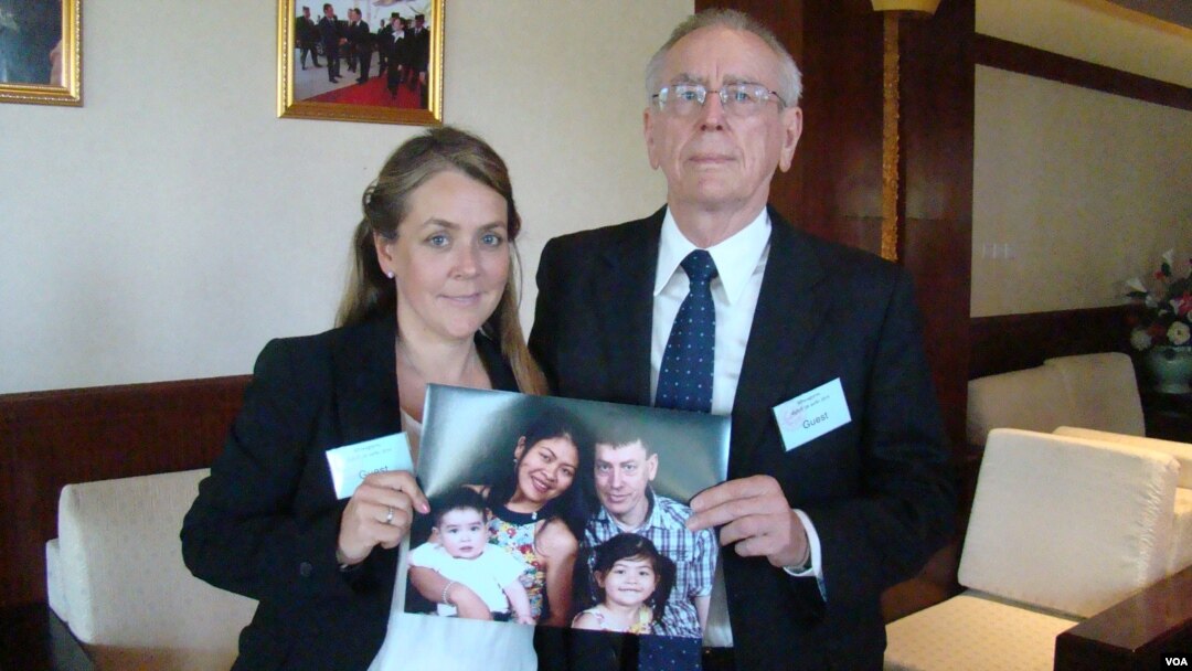 Melissa Rhodes-Smith and Geoff Rhodes hold a photo of Gavin Rhodes and his wife, Phoumalaysy and their children, in Vientiane, Laos, Nov. 28, 2014. (Ron Corben/VOA)