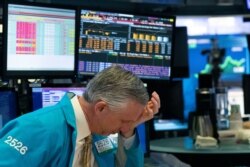 A trader holds his hand to his head after trading was halted at the New York Stock Exchange, March 18, 2020, in New York.