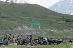 Indian army soldiers rest next to artillery guns at a makeshift transit camp before heading to Ladakh, near Baltal, southeast of Srinagar, June 16, 2020.