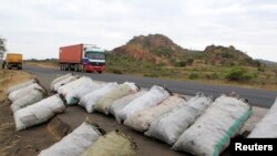 A trailer drives along the main Nairobi/Mombasa highway past sacks of charcoal, used for domestic cooking in many Kenyan homes, in Kibwezi. June 20, 2014. 