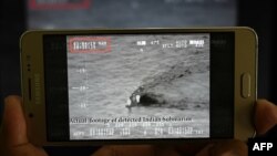 A Pakistani journalist watches a video released by Pakistan's Navy that allegedly shows an Indian submarine, on a smartphone in Islamabad on March 5, 2019.