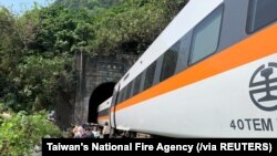 Para penumpang berjalan di samping kereta yang anjlok di terowongan di utara Hualien, Taiwan, 2 April 2021. (Foto: Dinas Pemadam Kebakaran Nasional Taiwan via Reuters)
