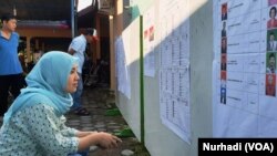 Pemilih memeriksa daftar legislatif yang dipasang di sebuah TPS di Sleman, DIY dalam Pemilu 2019. (Foto:VOA/Nurhadi)