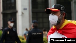 A man wearing a protective face mask, a Spanish flag and a t-shirt that reads: 'Go away Sanchez' attends a protest against the Spanish government's handling of the coronavirus crisis in Madrid, Spain May 16, 2020.