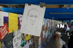 A drawing of George Floyd is displayed near signs created by protesters who demonstrated over his death, June 13, 2020, near the White House in Washington.