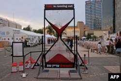 FILE: Supporters of Israeli hostages held in Gaza stand near an hourglass calling for their return outside Tel Aviv's Museum of Art on February 12, 2024.