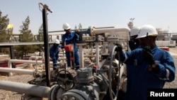 FILE - Workers check the valves at the Taq Taq oil field in Irbil, in Iraq's Kurdistan region. 