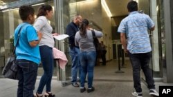 Una familia de inmigrantes muestra sus documentos para entrar en un tribunal de inmigración en un edificio de oficinas en el centro de Los Ángeles, California, el 30 de mayo de 2019.